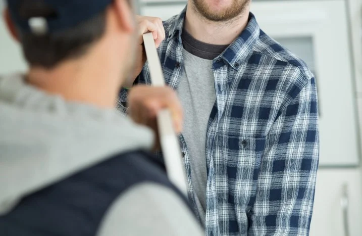 Zwei Personen halten eine Holzlatte.